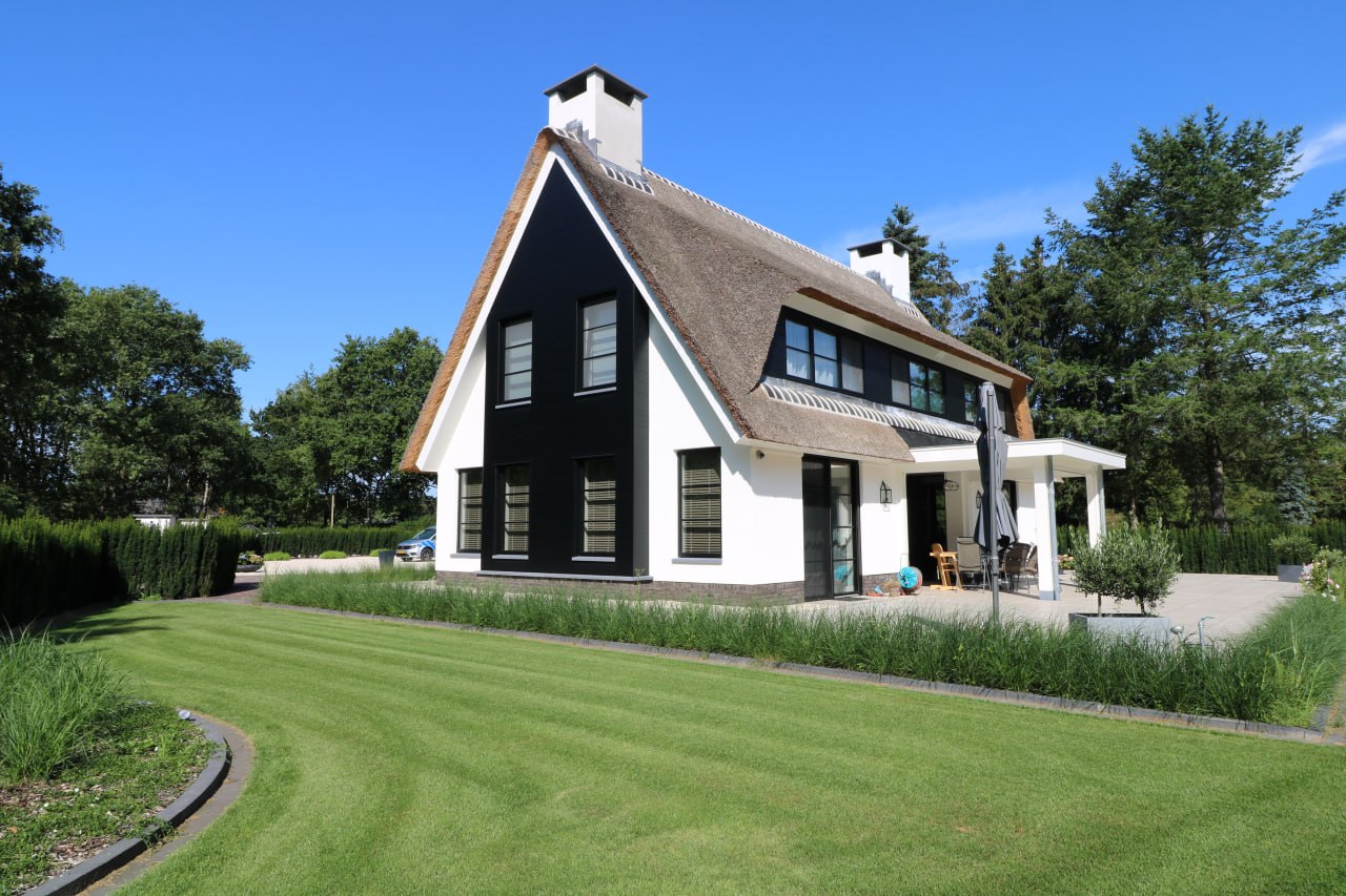 Thatched house with white facades and black accents